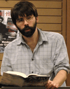 Escritor Joe Hill segurando um livro.